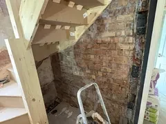 New loft staircase fitted against the old brick wall